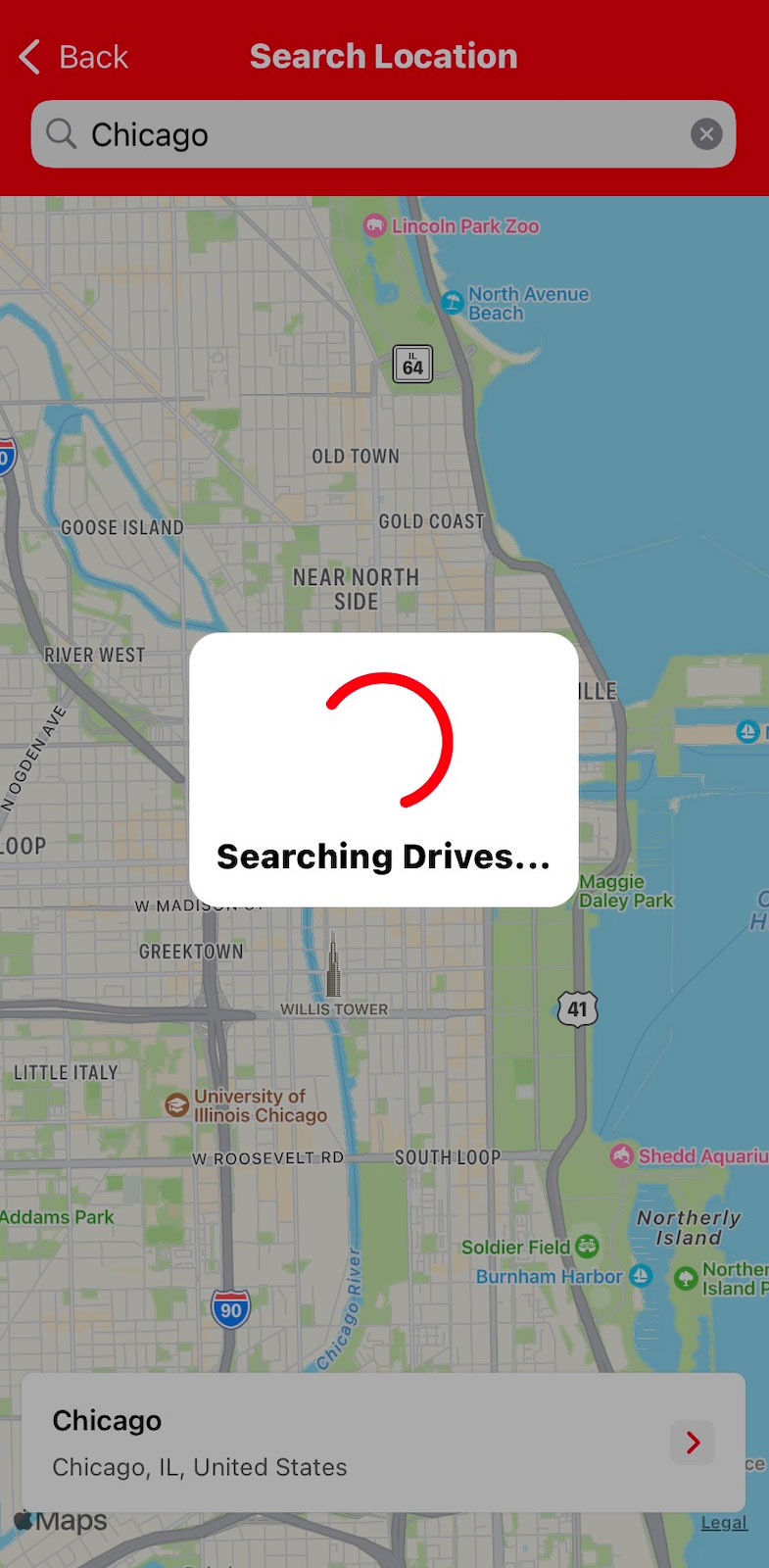 A screenshot from the American Red Cross Blood Donor App for a Blood Drive search in Chicago, IL. There is a loading indicator that says: "Searching Drives..." Behind the loading indicator is a dimmed map of Chicago.